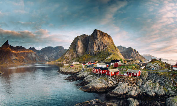 Norwegian fishing village at the Lofoten Islands in Norway. Dramatic sunset clouds moving over steep mountain peaks  nordland norway stock pictures, royalty-free photos & images